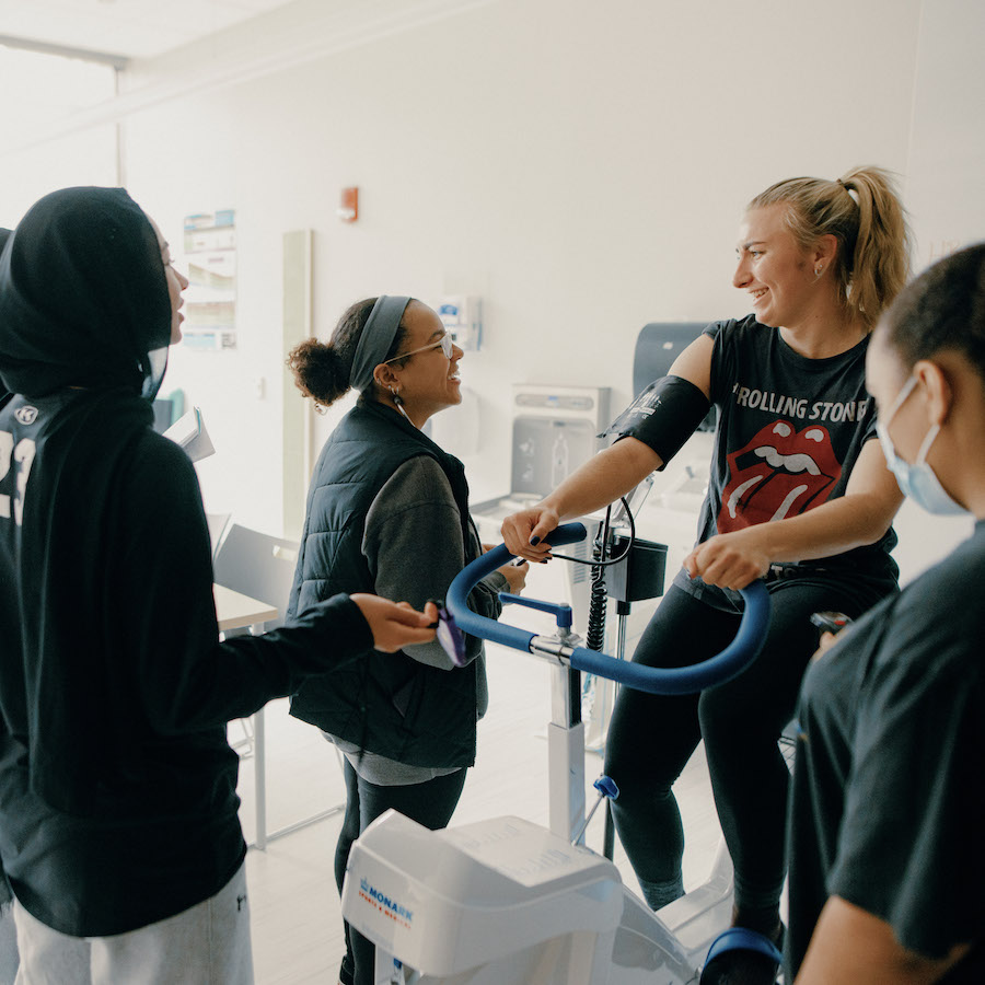 Student on exercise bike taking vitals