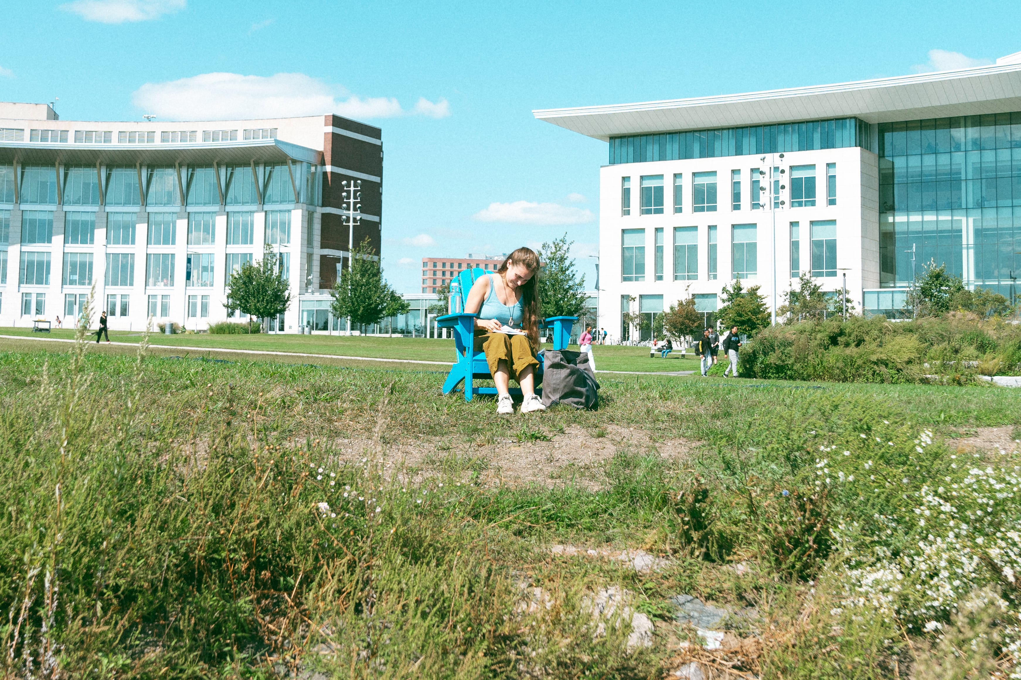 Female student sits in an adirondack chair on the Campus Center lawn
