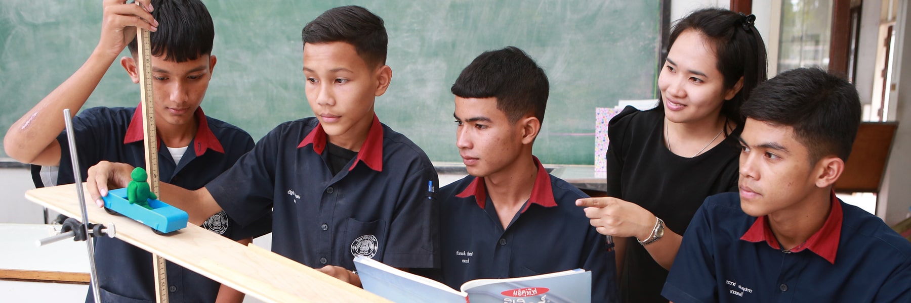 students stand horizontally at a table while conducting an experiment