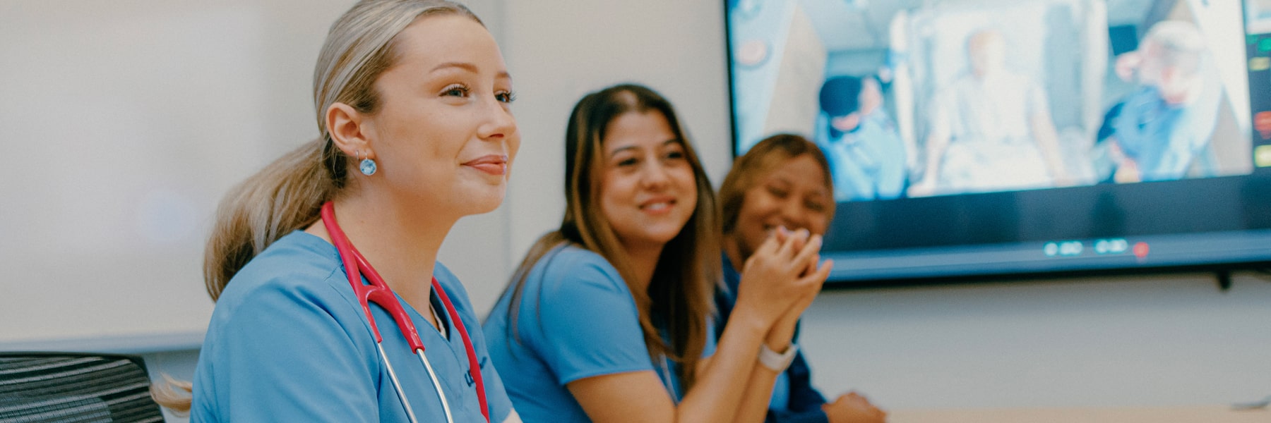 nursing students around conference table with image on presentation screen