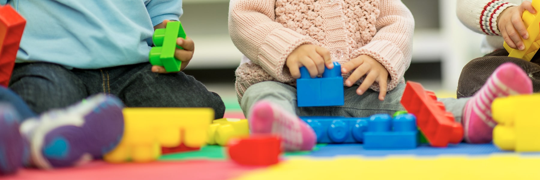 close up of babies from neck down playing with blocks