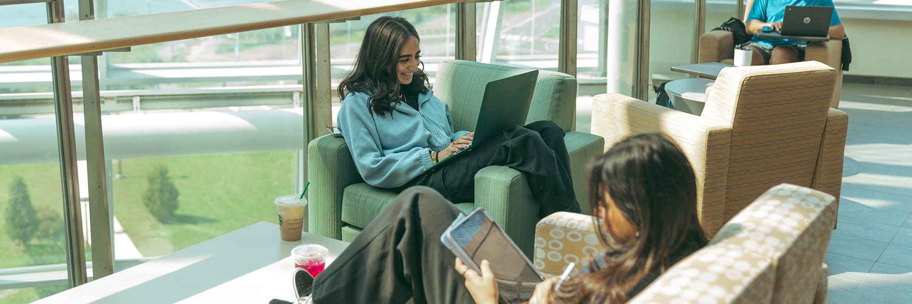 Student works on laptop near windows in University Hall.