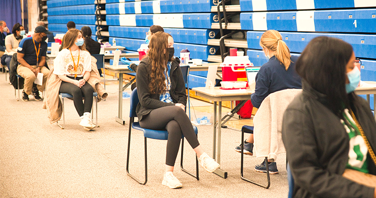 Students sitting in chairs in rows to get vaccine 