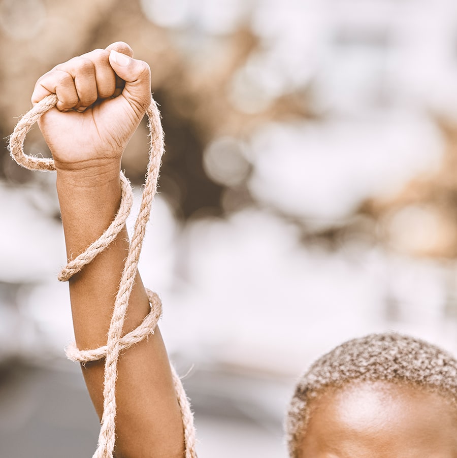 Hand, rope and fist protest slavery for freedom and human rights against an urban background.
