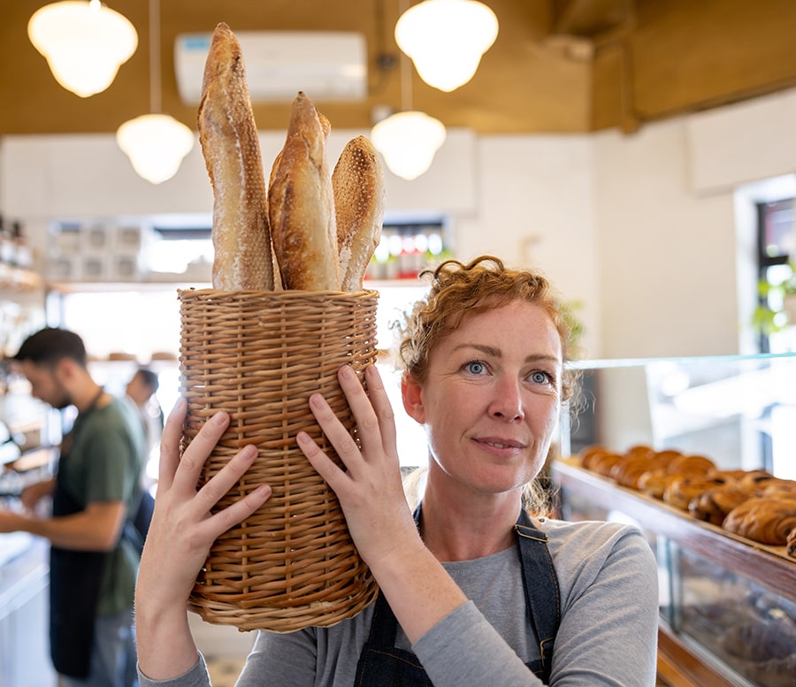 Woman holding basket of baguettes in a bakery