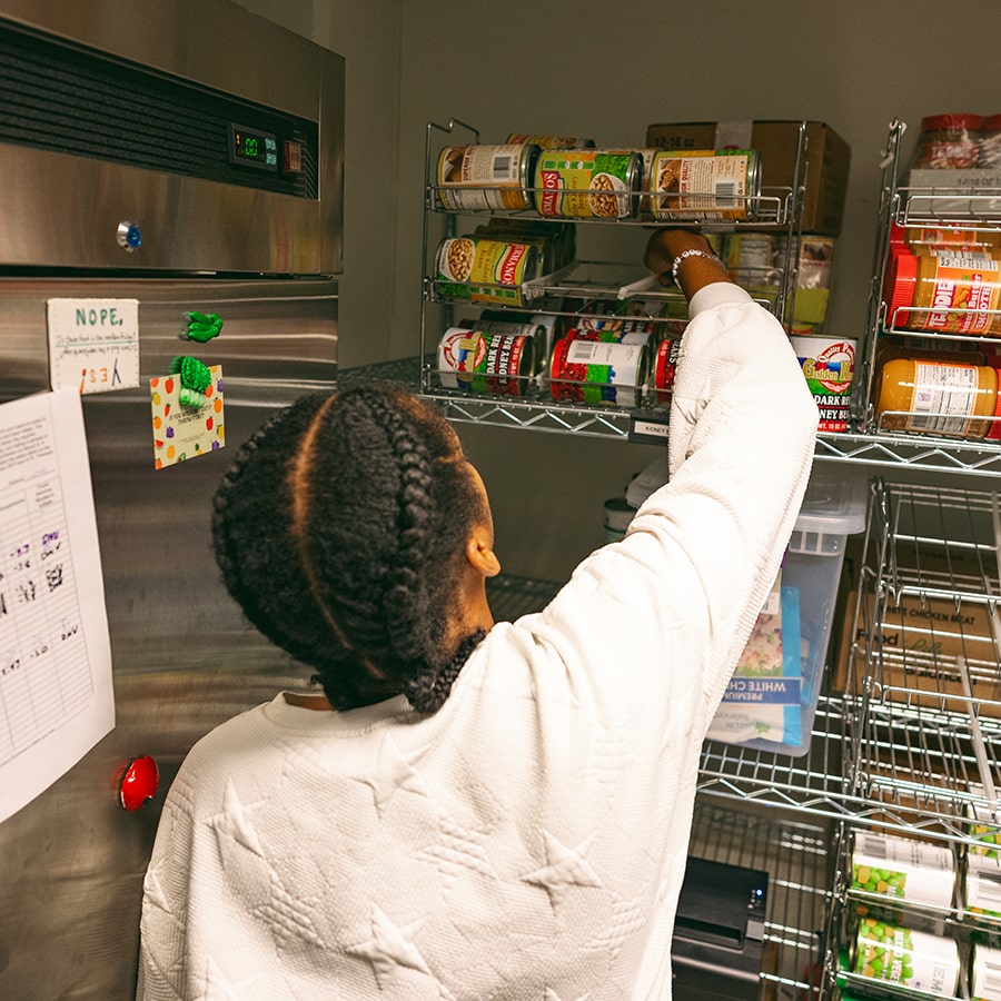 u-access staff reaches for can of food higher on a shelf