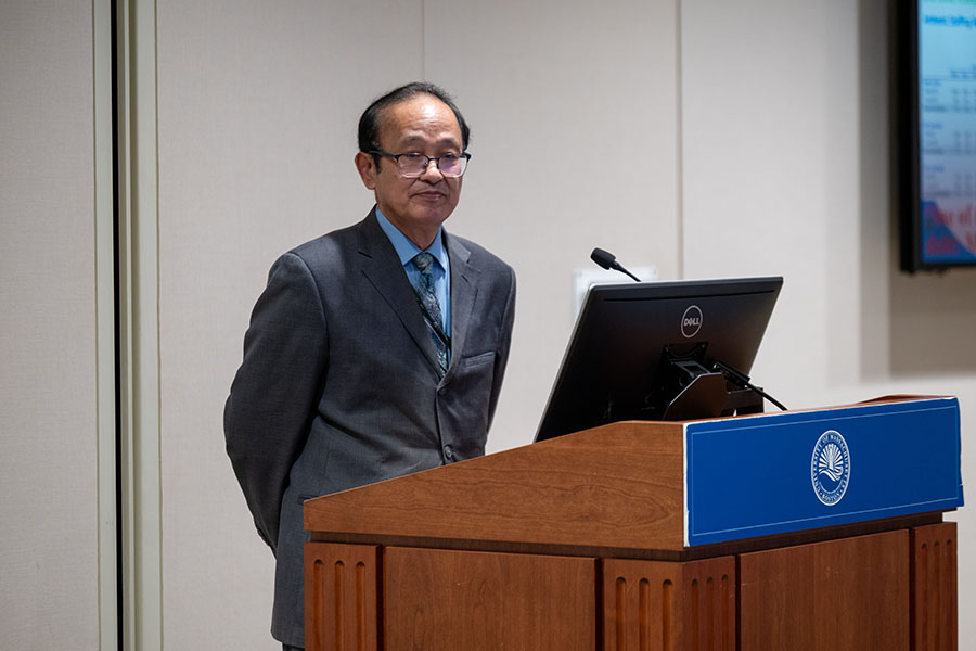 Zong-Guo Xia stands at a podium, giving his lecture.