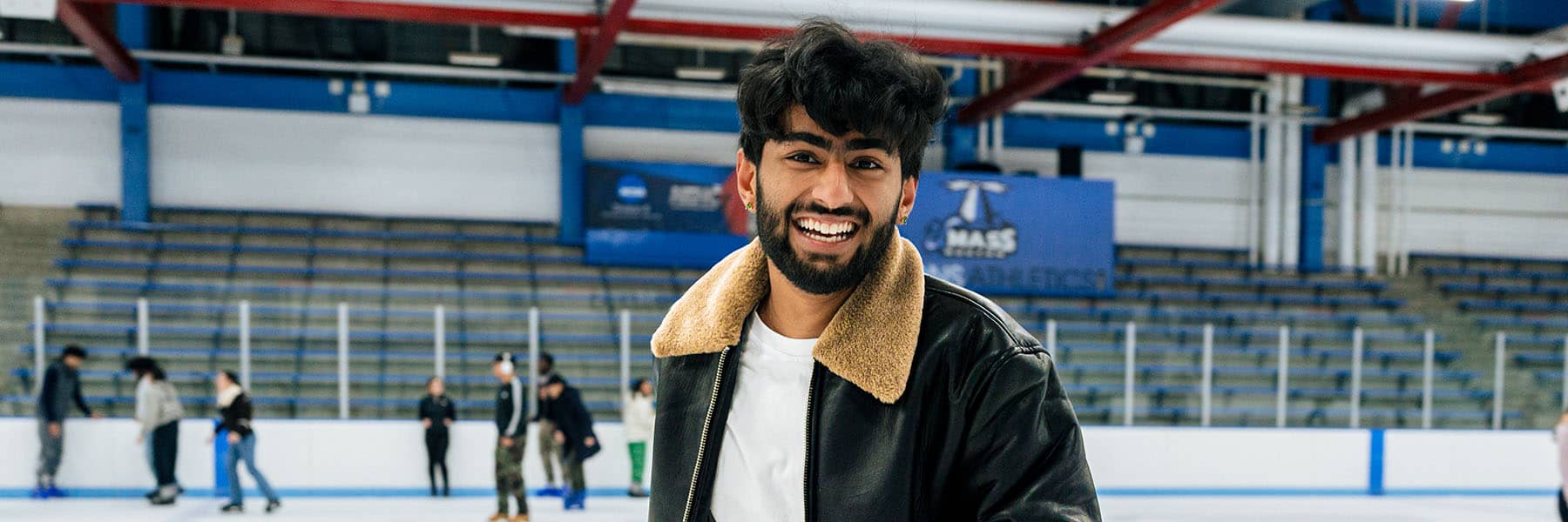 Male student posing while skating on the UMass Boston ice rink