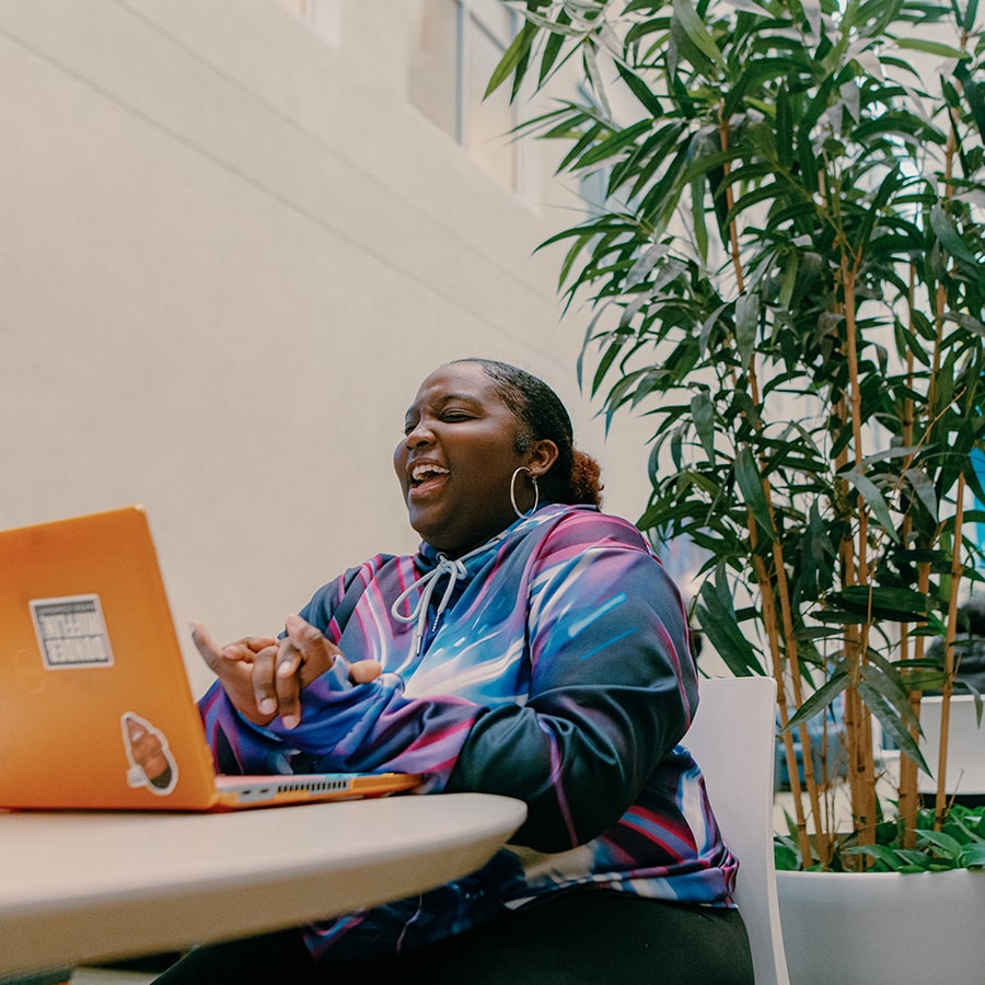 Black female student in campus center laughing shot from below