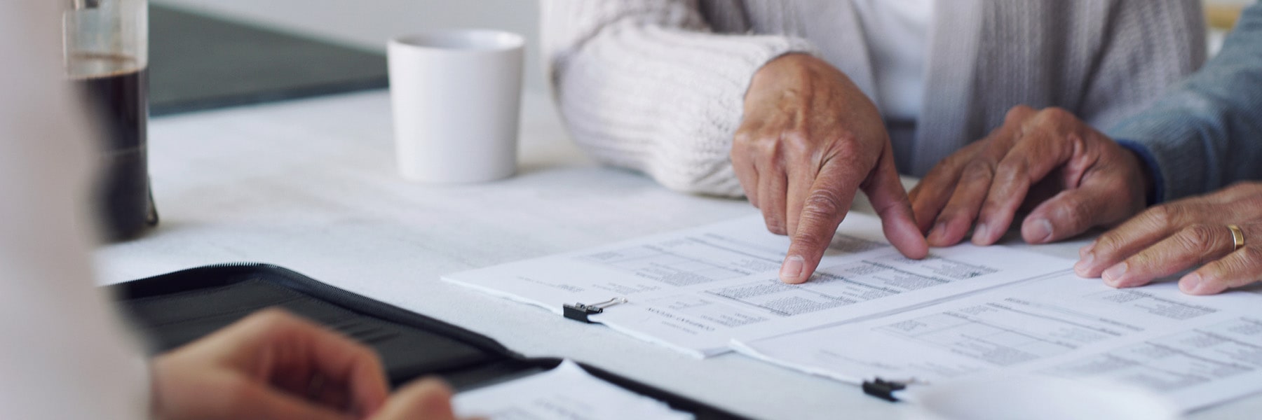 hands touching financial documents next to coffee cup.