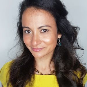 Woman with long dark brown hair and a yellow shirt